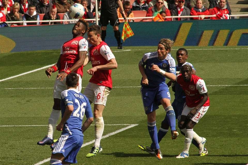 Alex Song (left) and Laurent Koscielny (6) rise for the ball as Fernando Torres (9) awaits.